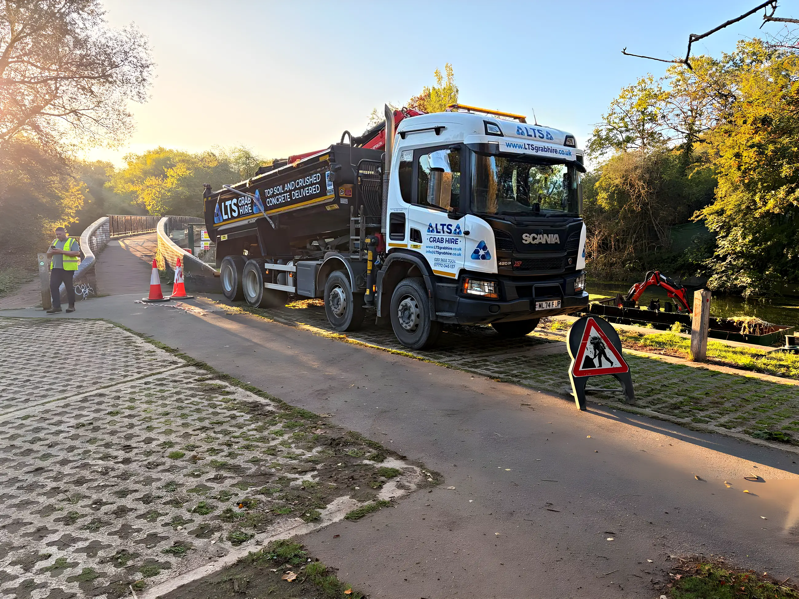 An eight-wheel grab lorry at a riverside job in low evening light
