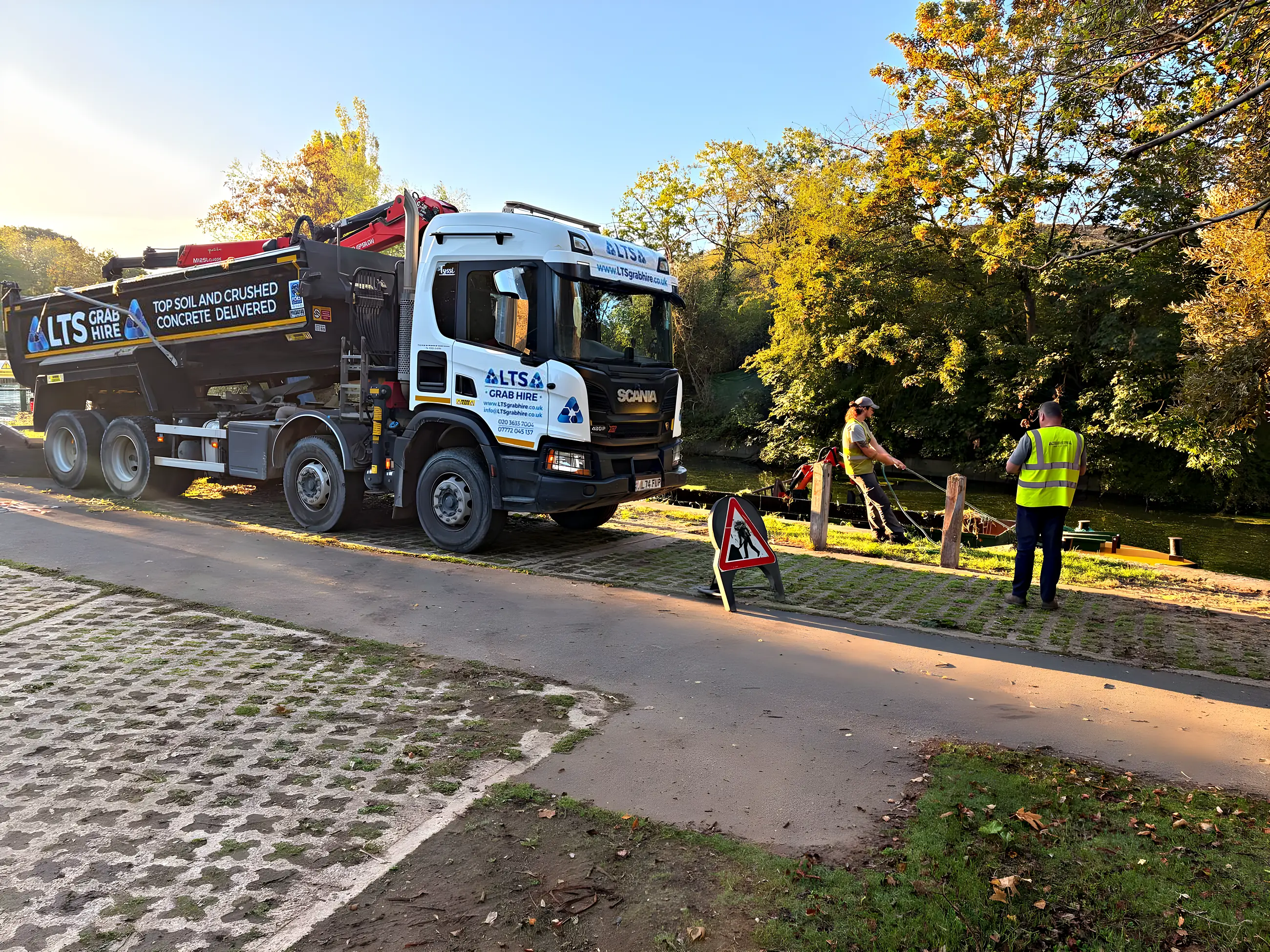 A grab lorry on a towpath clearance with the crew working beside the water