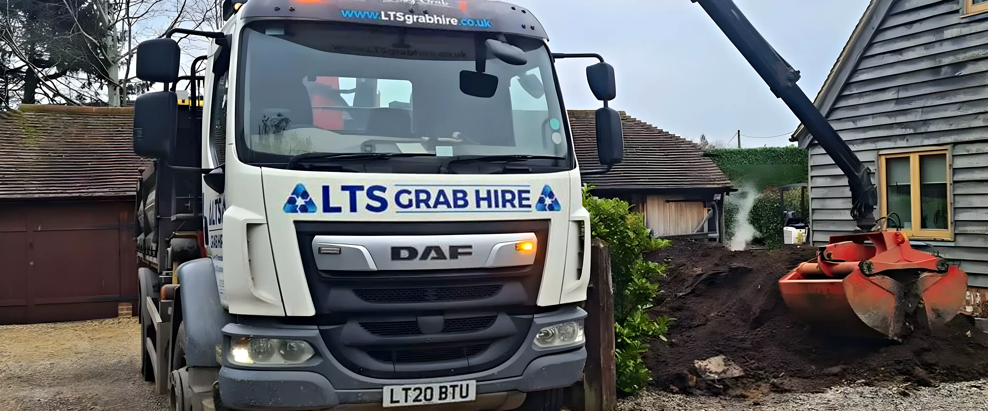 A grab lorry with its bucket in a heap of excavated soil