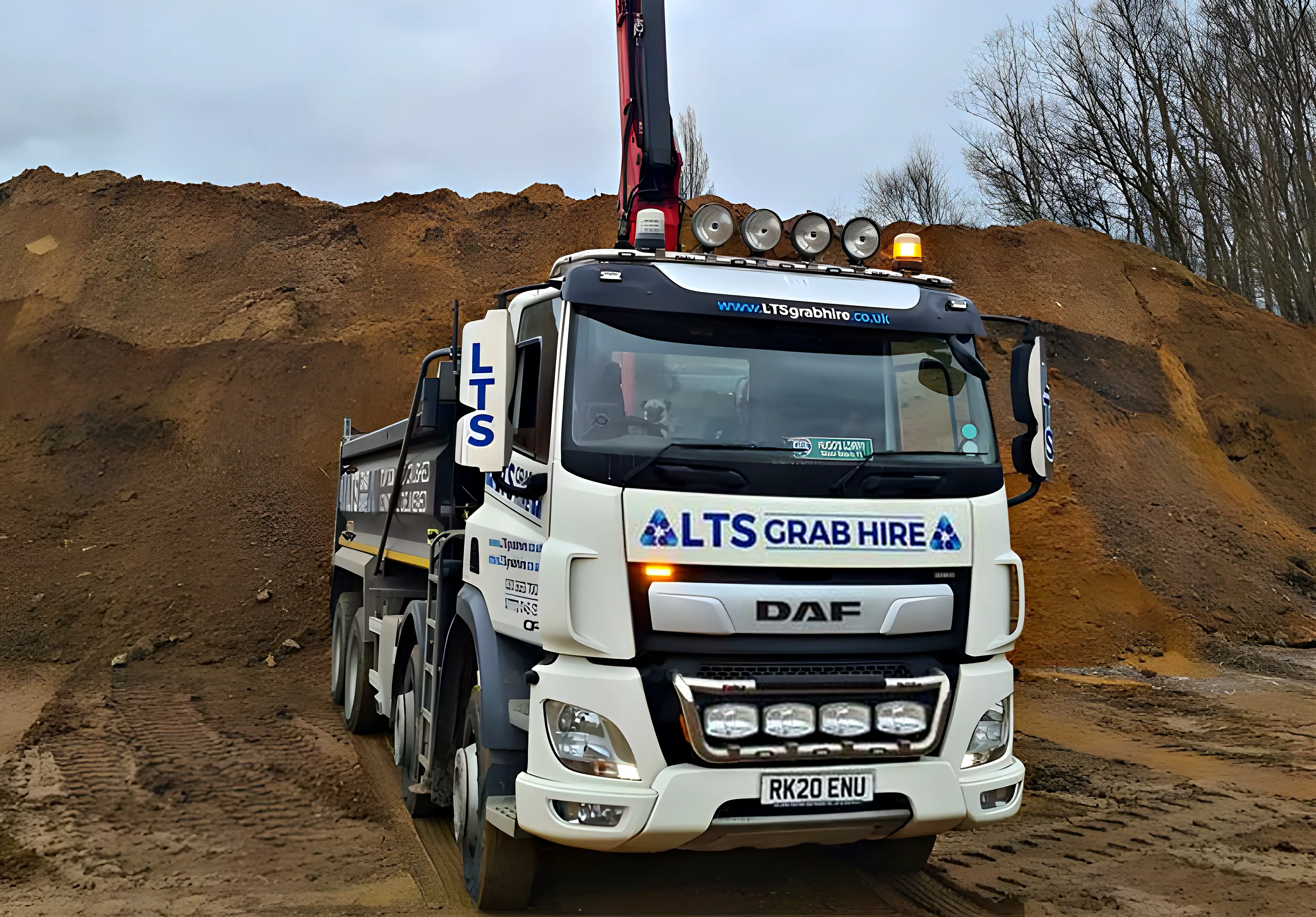 A grab lorry parked beside a large heap of excavated soil